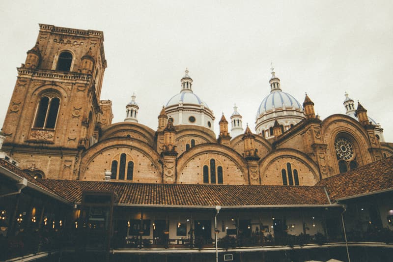 The brick tower and blue-and-white domes of Cuenca's New Cathedral above a tiled colonial roof